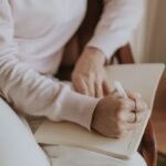 A person journaling in a cozy room with a cup of coffee. Warm and inviting atmosphere.