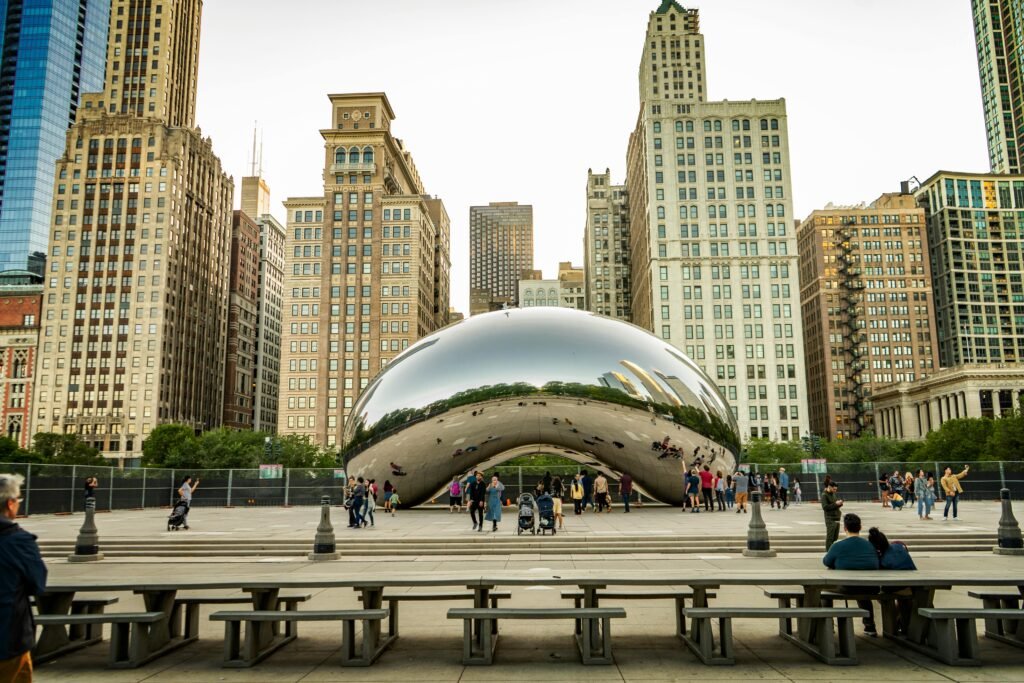 Tourists gather around Cloud Gate at Millennium Park, Chicago, reflecting the city skyline.