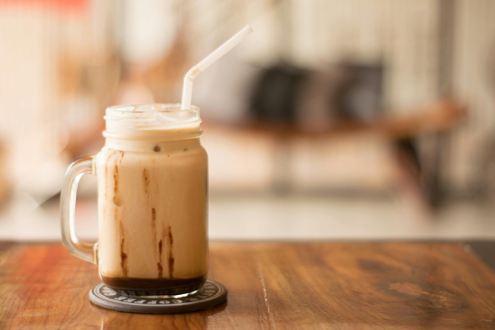 Close-up of iced coffee in a mason jar on a wooden table, perfect for a café vibe.