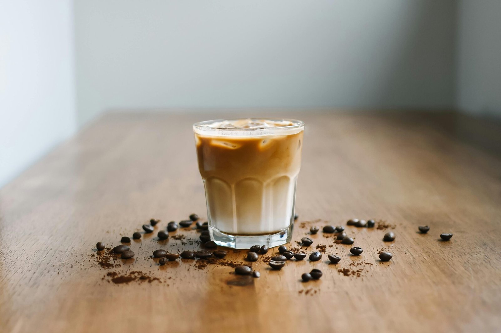 Refreshing iced latte with coffee beans on a wooden table surface.