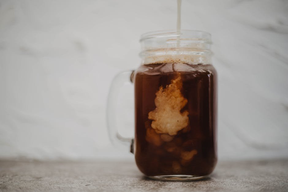 Close-up of cold brew coffee with cream swirling in a mason jar. Perfect for beverage themes.