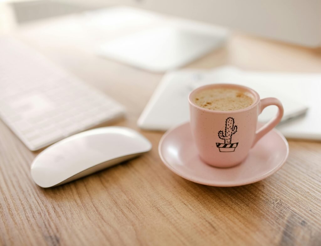 A close-up of a cappuccino in a cactus-decorated cup on a sleek workspace.