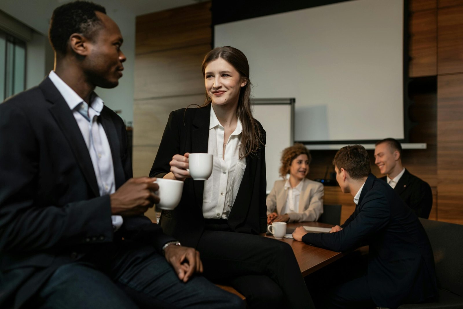 Group of diverse professionals enjoying a coffee break during a business meeting in a conference room.