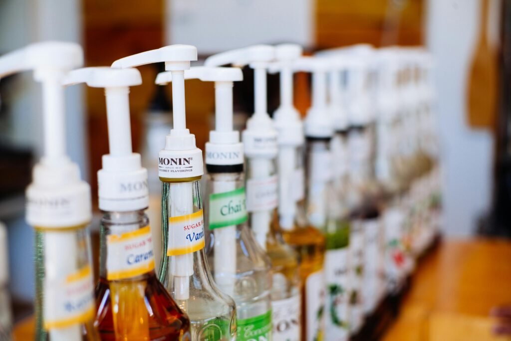 Row of coffee syrup pumps in various flavors, ideal for cafes.