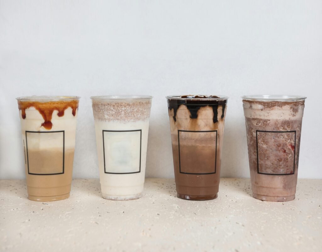 A variety of iced coffee beverages in clear plastic cups, showcasing different flavors and layers.