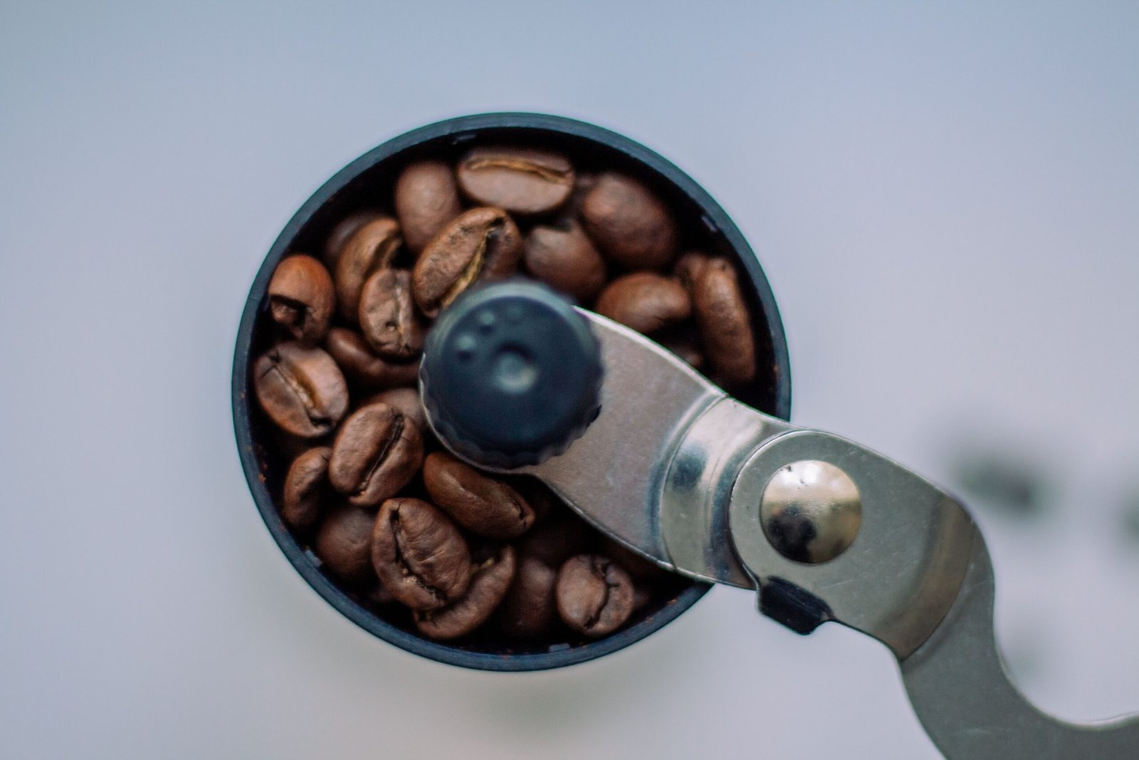 best coffee grinder, Close-up of roasted coffee beans in a manual grinder shot from above.