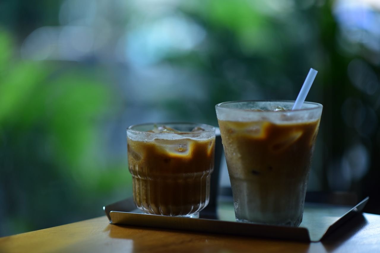 Two chilled iced coffees with a straw on a table, perfect for a warm day.