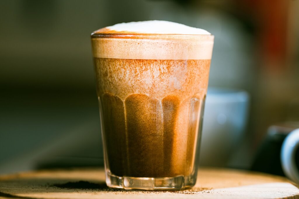 A rich, frothy cappuccino captured in a clear glass, emphasizing texture and warmth. Starbucks aerocano review